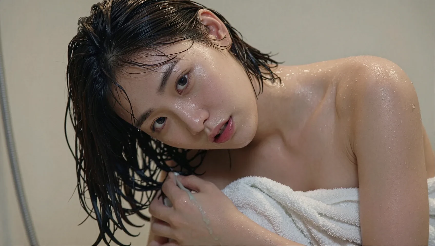 Wide frame of a fictional AI character with wet hair wrapped in a white towel in a bathroom